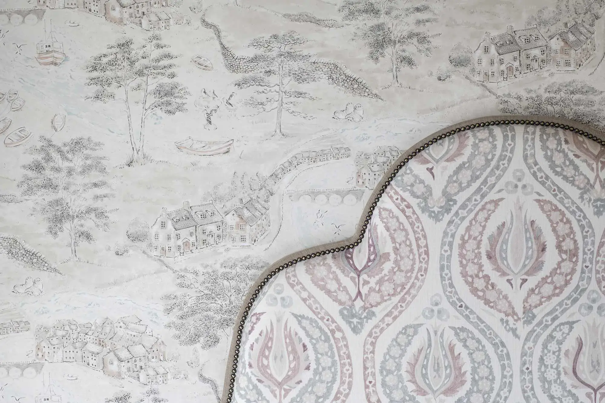 Top of a bed in front of countryside themed wallpaper