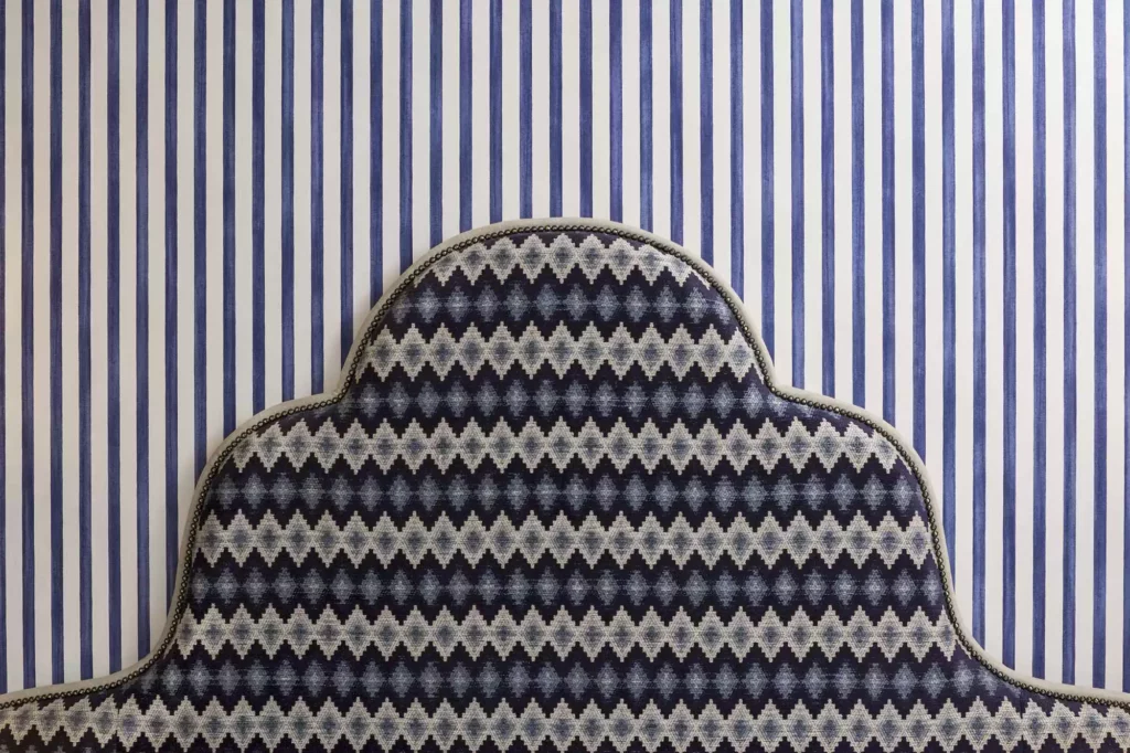 Top of a bed in front of blue and white striped wallpaper