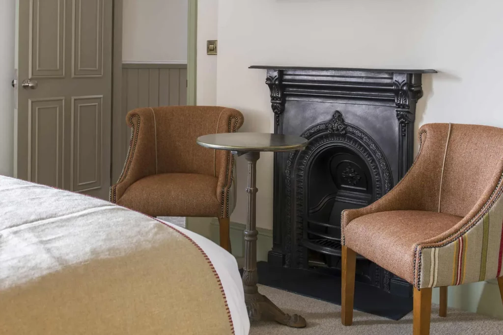 Two chairs and a tabletop next to a fireplace